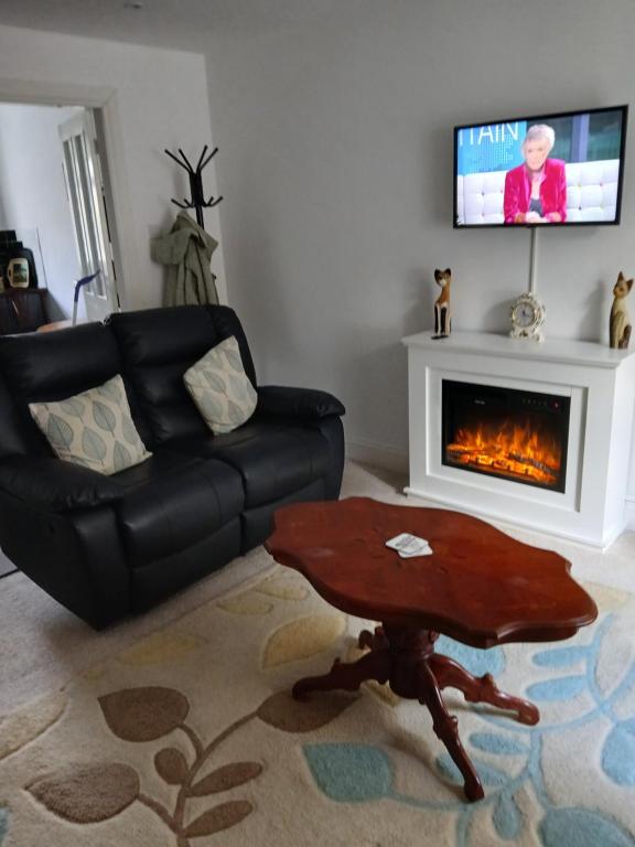 a living room with a couch and a table and a fireplace at Couple's Retreat-West Kilbride in Seamill