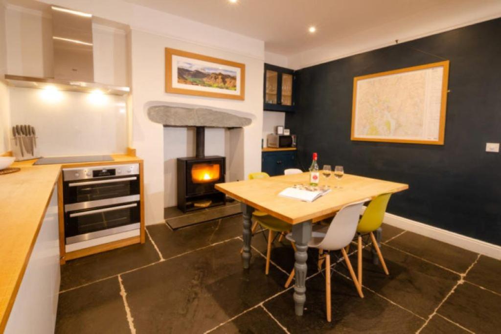 a kitchen with a wooden table and a fireplace at Holmdale - Central Ambleside in Ambleside