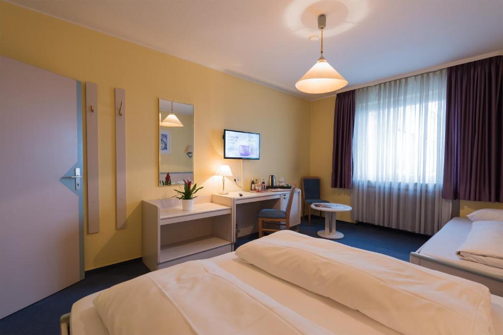 a hotel room with a bed and a desk at Tagungshotel Höchster Hof in Frankfurt