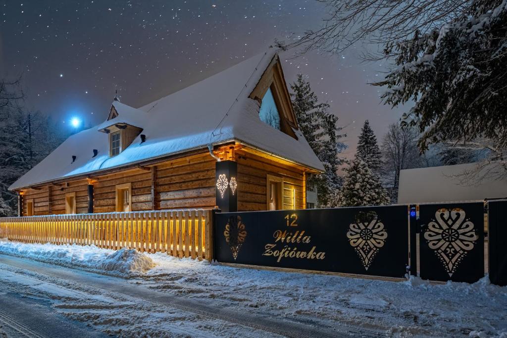 eine Blockhütte im Schnee bei Nacht in der Unterkunft Willa Zofiówka in Zakopane