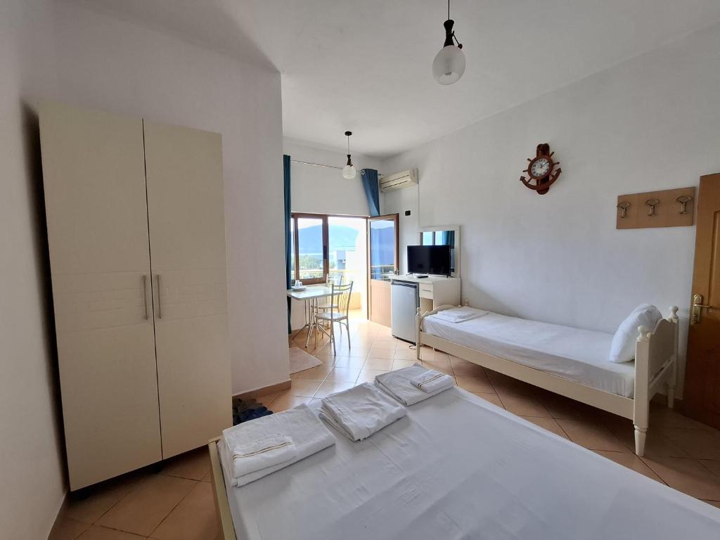 a bedroom with two beds and a kitchen with a table at Hotel Sirena in Vlorë