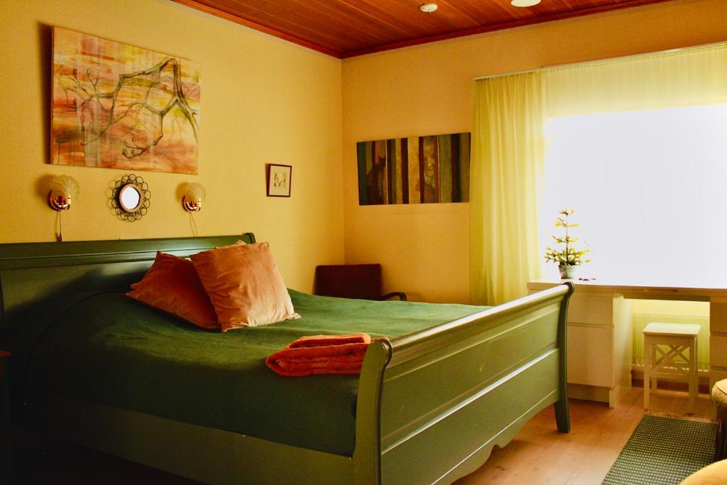 a bedroom with a green bed and a window at Keltainen talo - tilava huvila lähellä Saloa in Vartsala
