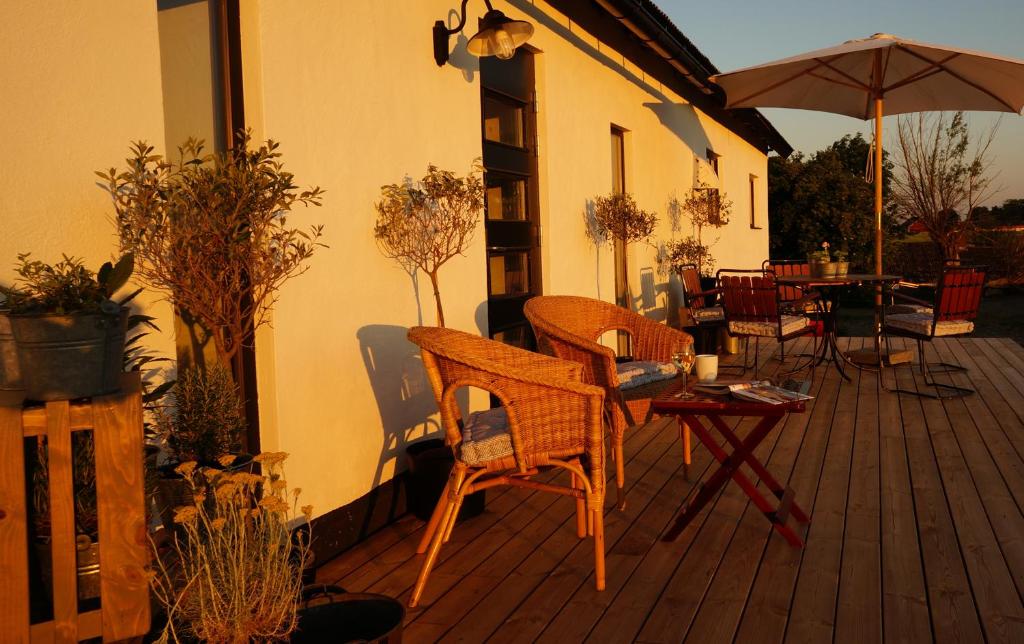 a deck with chairs and tables and an umbrella at Almbacka Logi in Skivarp