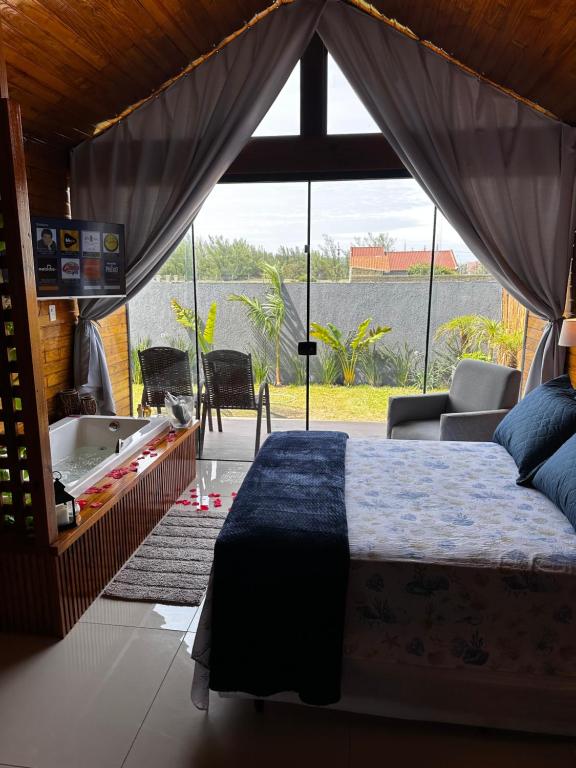 ein Schlafzimmer mit Bett und Blick aufs Wasser in der Unterkunft Chalés DEL MAR- com banheira in Tramandaí