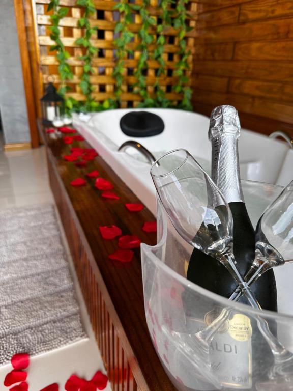 a bath tub filled with bottles of wine and glasses at Chalés DEL MAR- com banheira in Tramandaí