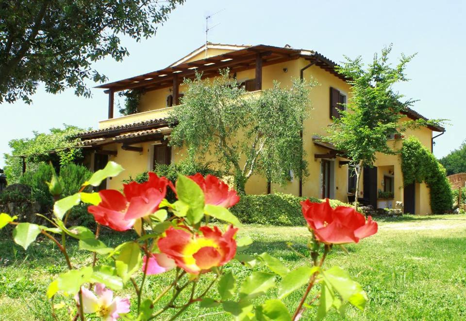 a yellow house with red flowers in front of it at La Casa di Gelsomino in Massa Martana