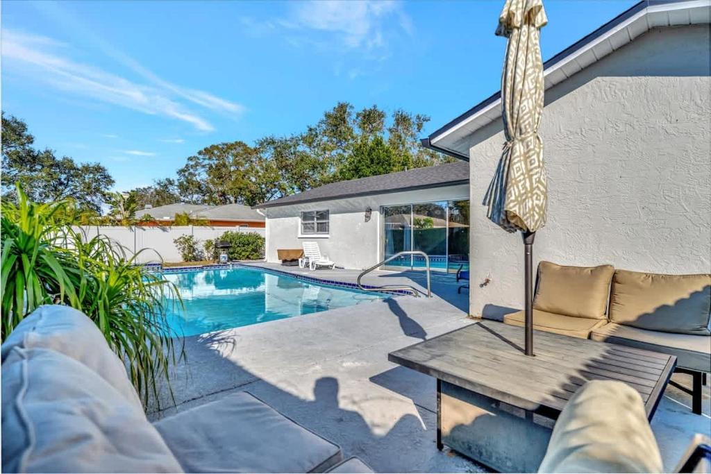 a swimming pool with a bench and an umbrella at Heated Pool 3b&2b home in Largo