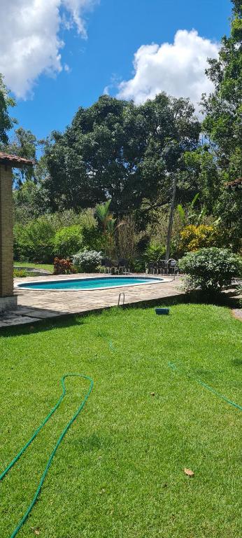 a hose on the grass next to a swimming pool at Flat 01 Carvalhos de Aldeia km5 in Recife