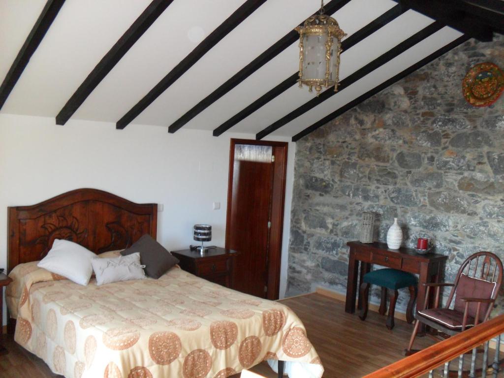 a bedroom with a bed and a stone wall at Fazenda do Sousinha in Funchal