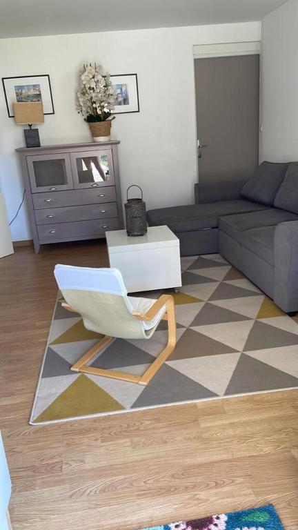 - un salon avec une chaise blanche et un canapé dans l'établissement Appartement Confort, à Marguerittes