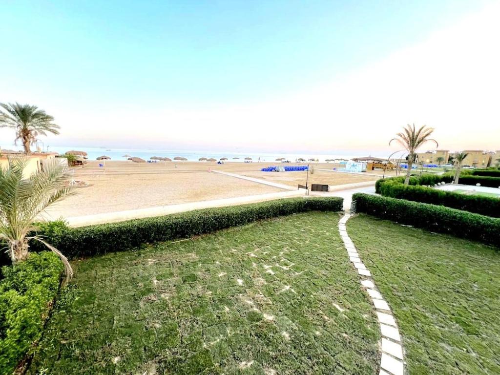 a grassy field with a beach in the background at First row villa on the sea in the village of Aquarius family only in Ain Sokhna