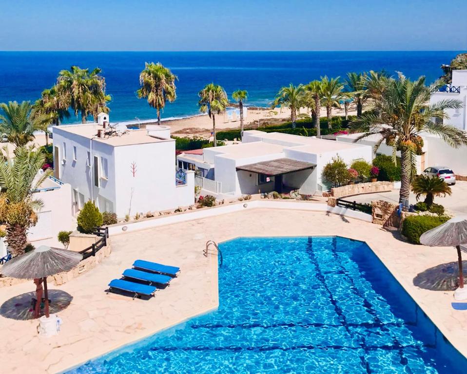 eine Luftansicht auf einen Pool und den Strand in der Unterkunft Sunset Deluxe Villa and Studios in Paphos City