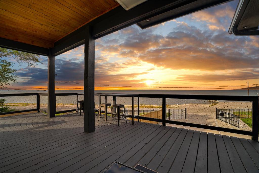 a deck with a view of the ocean at sunset at Waterfront Home with Views - Hot Tub & Movie Theatre in Bacliff
