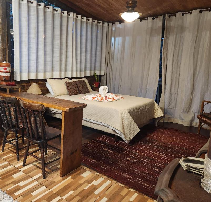 une chambre avec un lit et une table avec des chaises dans l'établissement Chalé Rustic House, à Campos do Jordão