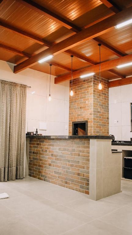 a kitchen with a brick wall and wooden ceilings at Tiny House - Centro Concórdia in Concordia