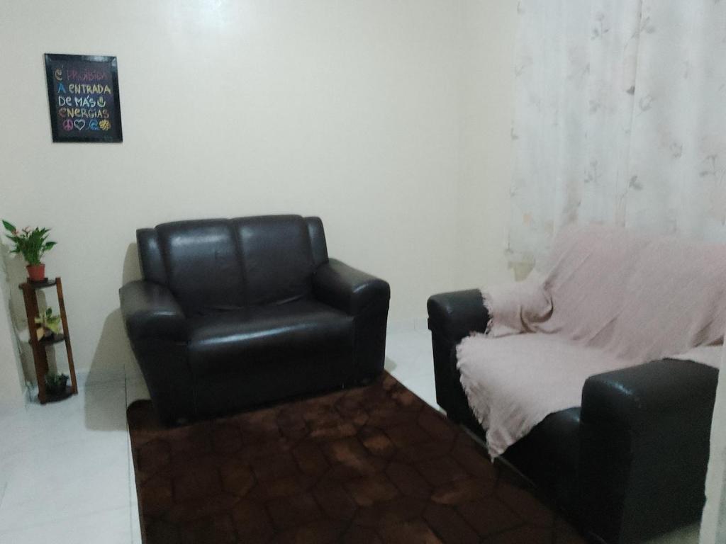 a black leather chair and a couch in a room at Casa Familiar no Centro de Angra in Angra dos Reis