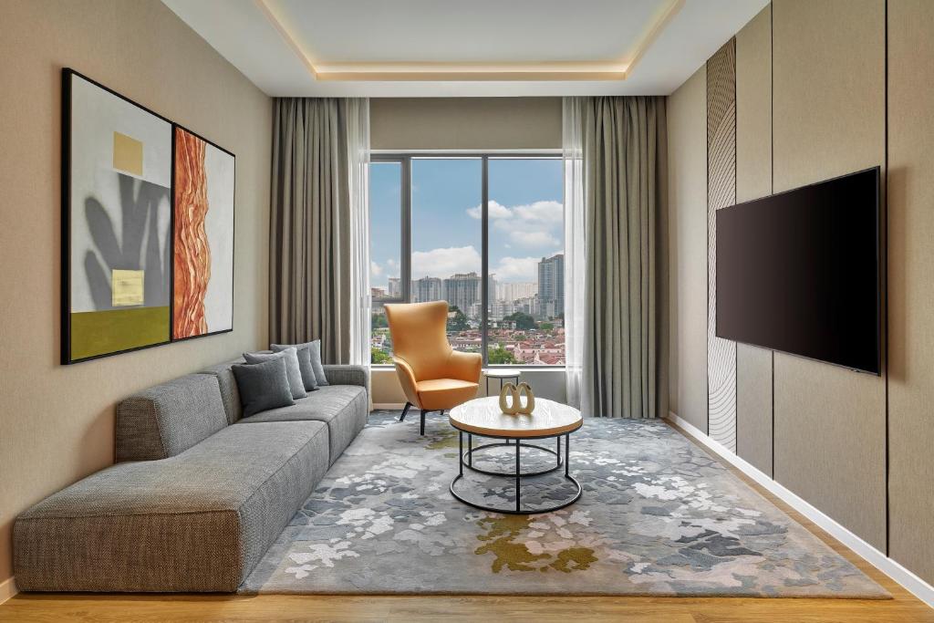 A separate sitting room with a sofa, television, lounge chair, and city view.