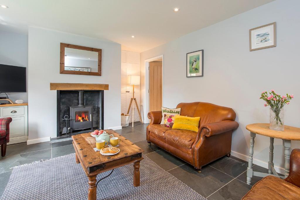 ein Wohnzimmer mit einem Ledersofa und einem Kamin in der Unterkunft Bwthyn Clyd in Haverfordwest