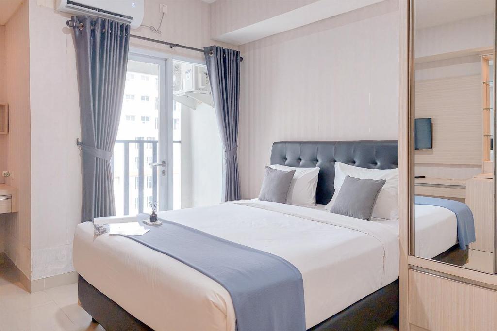 a bedroom with a large bed with a large window at Cozy Living Studio at Paramount Skyline Apartment By Travelio in Tangerang
