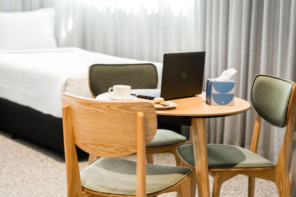 a hotel room with a table with a laptop and chairs at Mary MacKillop Place in Sydney