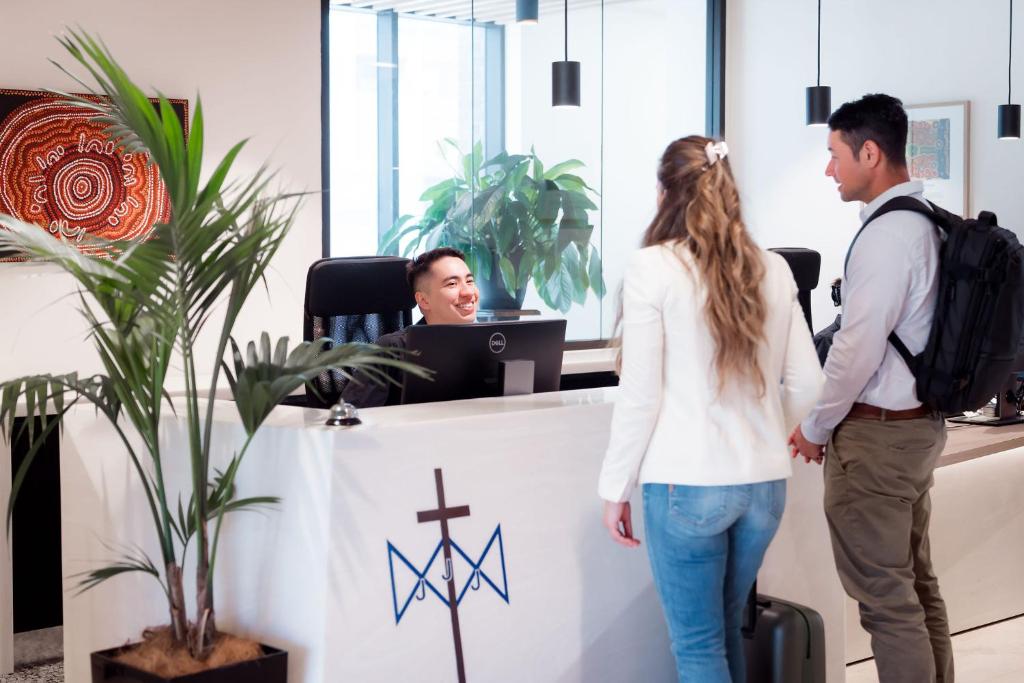 a man and woman standing at a reception desk in an office at Mary MacKillop Place in Sydney