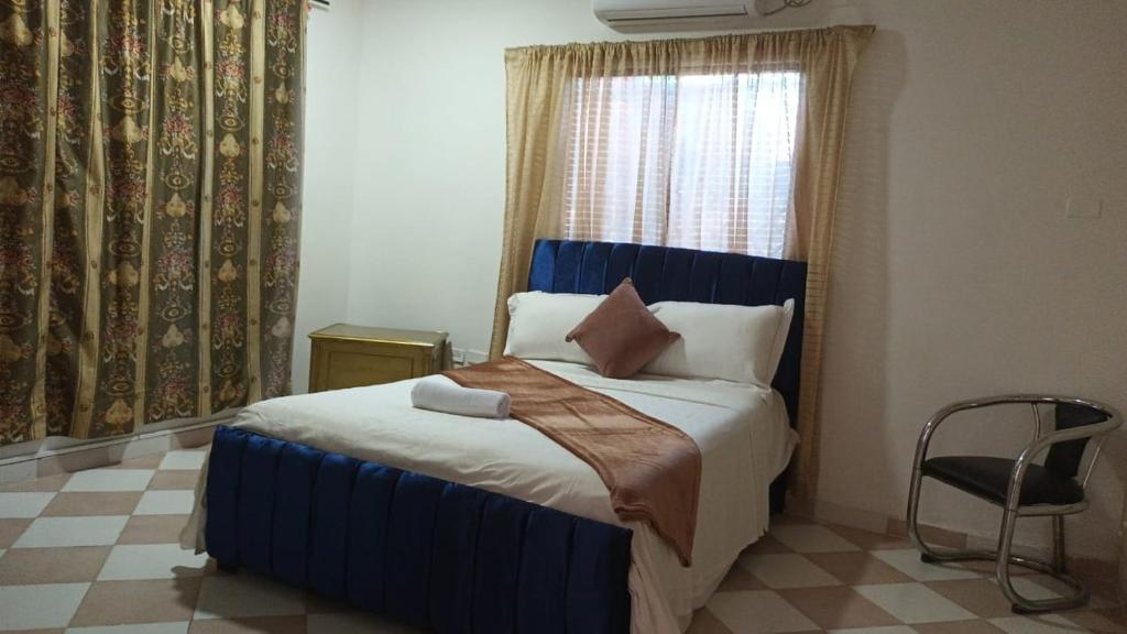 une chambre avec un lit bleu avec une fenêtre et une chaise dans l'établissement Prado alto inn, à Barranquilla