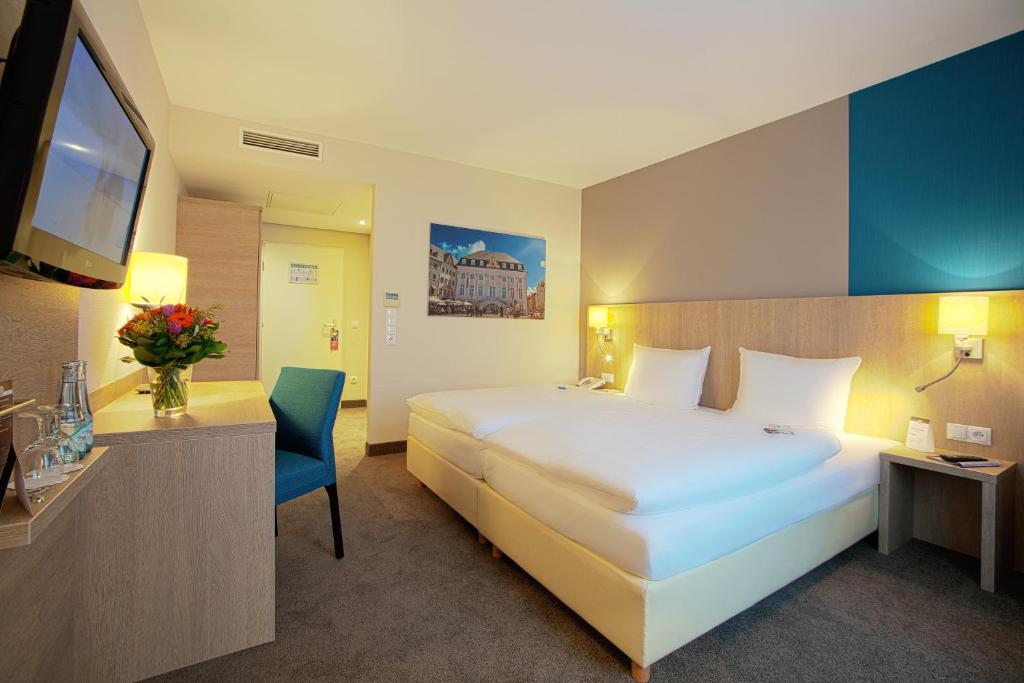 a hotel room with a large bed and a television at President Hotel in Bonn