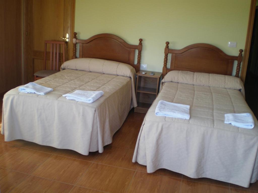 Hostal Catro Ventos في لوغو: سريرين في غرفة الفندق عليها مناشف