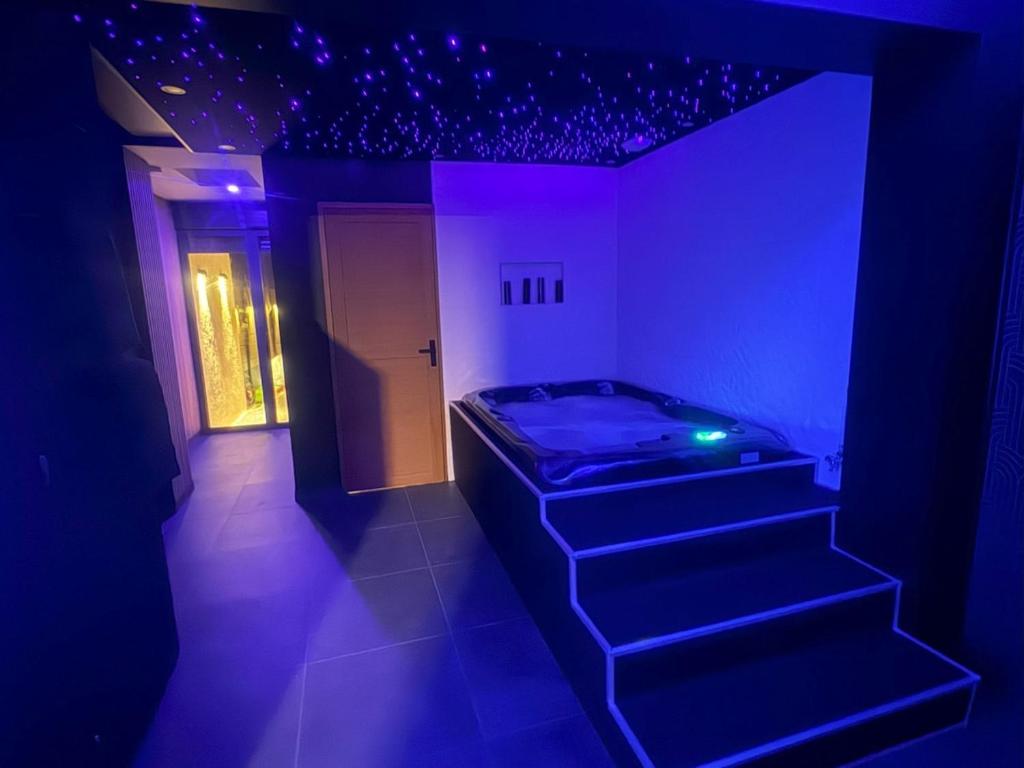 a room with a bed and a staircase with purple lights at Sweety's Eden Jacuzzi - Spa privé Sauna Cinéma room Jardin - Terrasse centre-ville in Le Mans