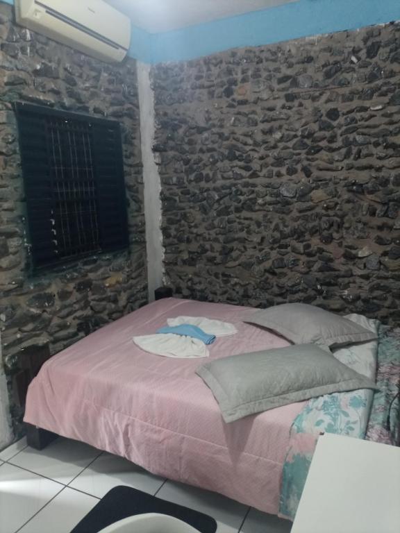 Un dormitorio con una cama con una pared de piedra. en Quarto de Pedra, en Cuiabá