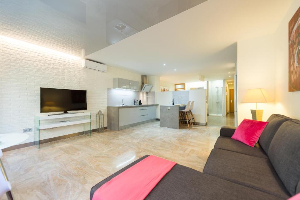 sala de estar amplia con sofá y cocina en Suites Garden Loft El Greco, en Las Palmas de Gran Canaria