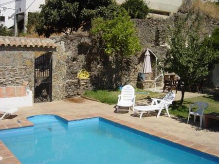 une piscine avec deux chaises et un parasol dans l'établissement Cortijo Retarta Jubrique, à Jubrique