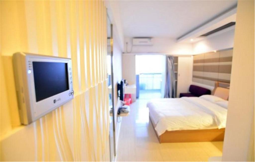 a hotel room with a bed and a flat screen tv at Nanning Qingzhou Rental Apartments in Nanning