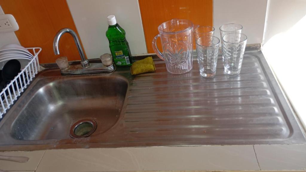 a kitchen sink with glasses and a bottle on it at Apartamento #5 in Puerto Colombia
