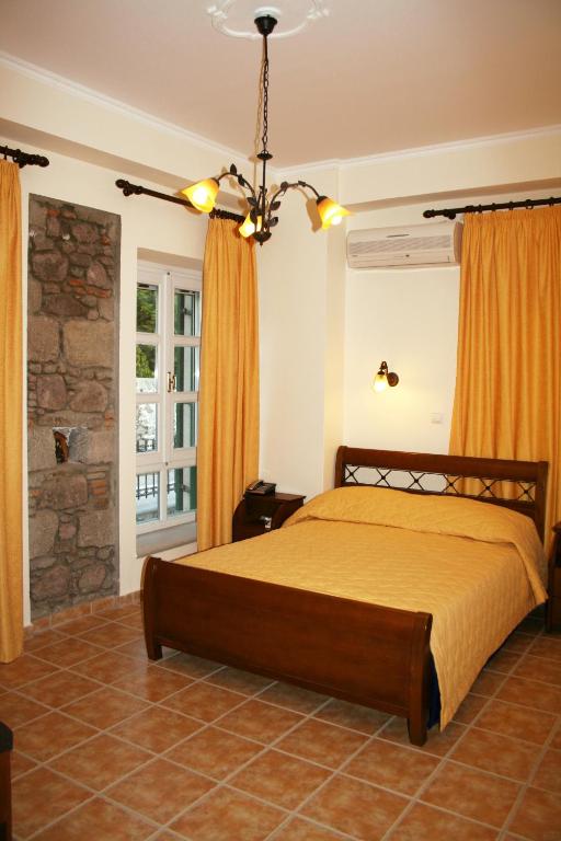 a bedroom with a bed and a chandelier at Artemis Traditional Hotel in Myrina