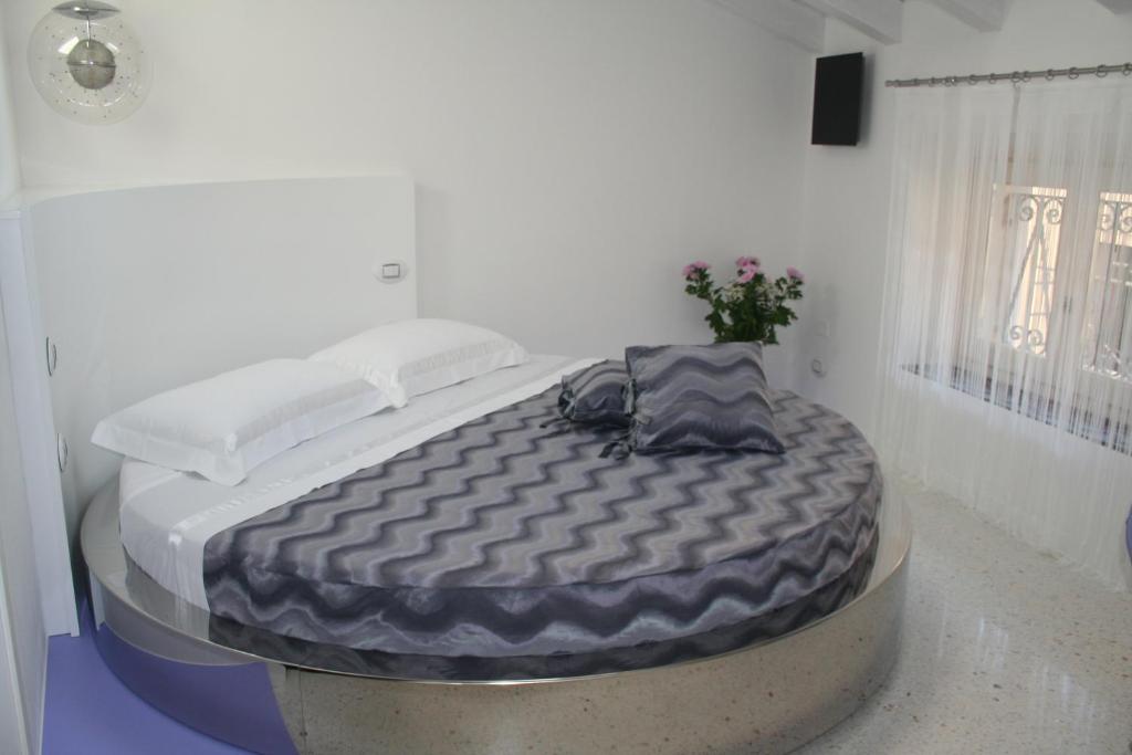 a large bed in a white room with at Ca' Ottocento in Lazise