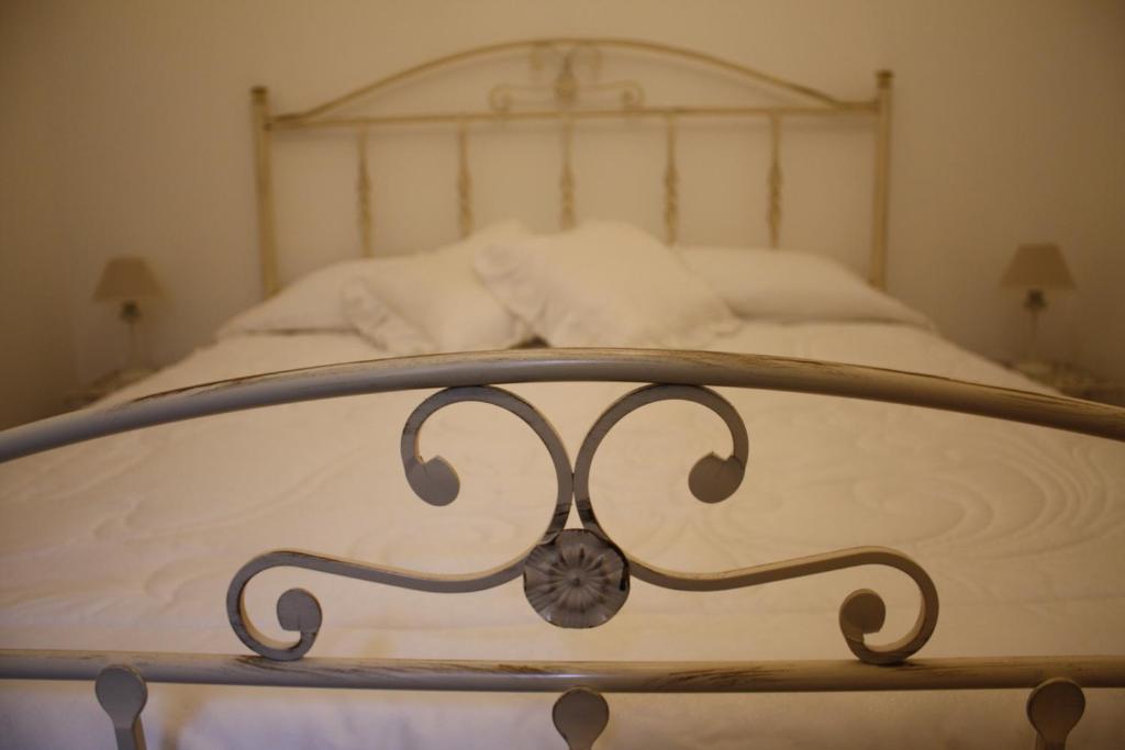 un letto con lenzuola bianche e telaio in legno di La Conchiglia Tra i Due Mari a Trapani