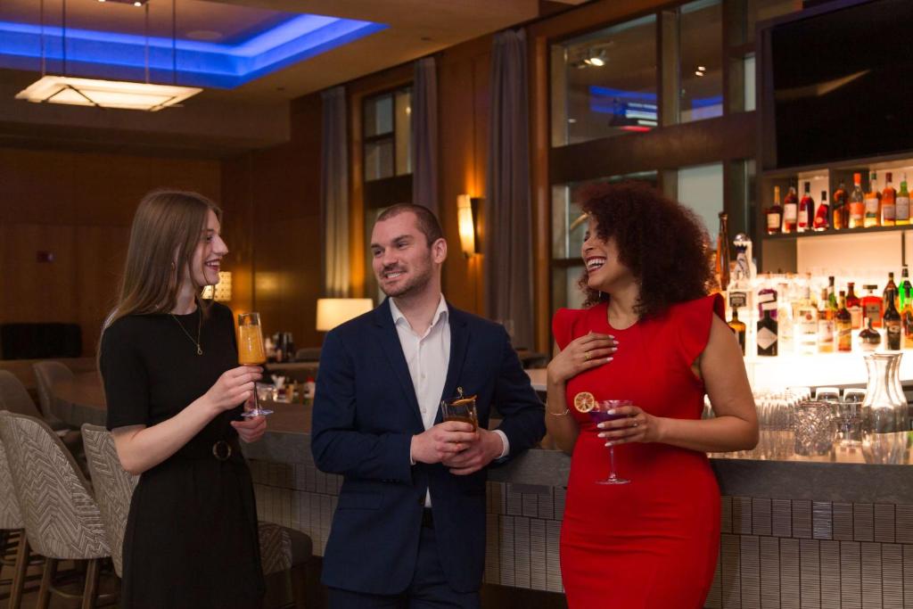 three people standing in a bar holding wine glasses at Grand Hyatt Seattle in Seattle