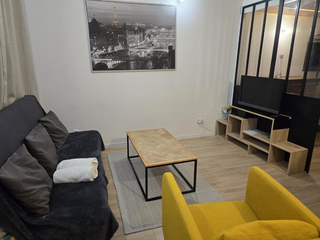 a living room with a couch and a table and a tv at La mezzanine Rouennaise in Rouen
