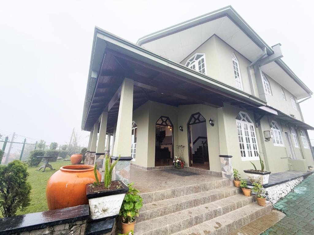 een wit huis met een vaas op de trap bij Kings Villa Nuwara Eliya in Nuwara Eliya