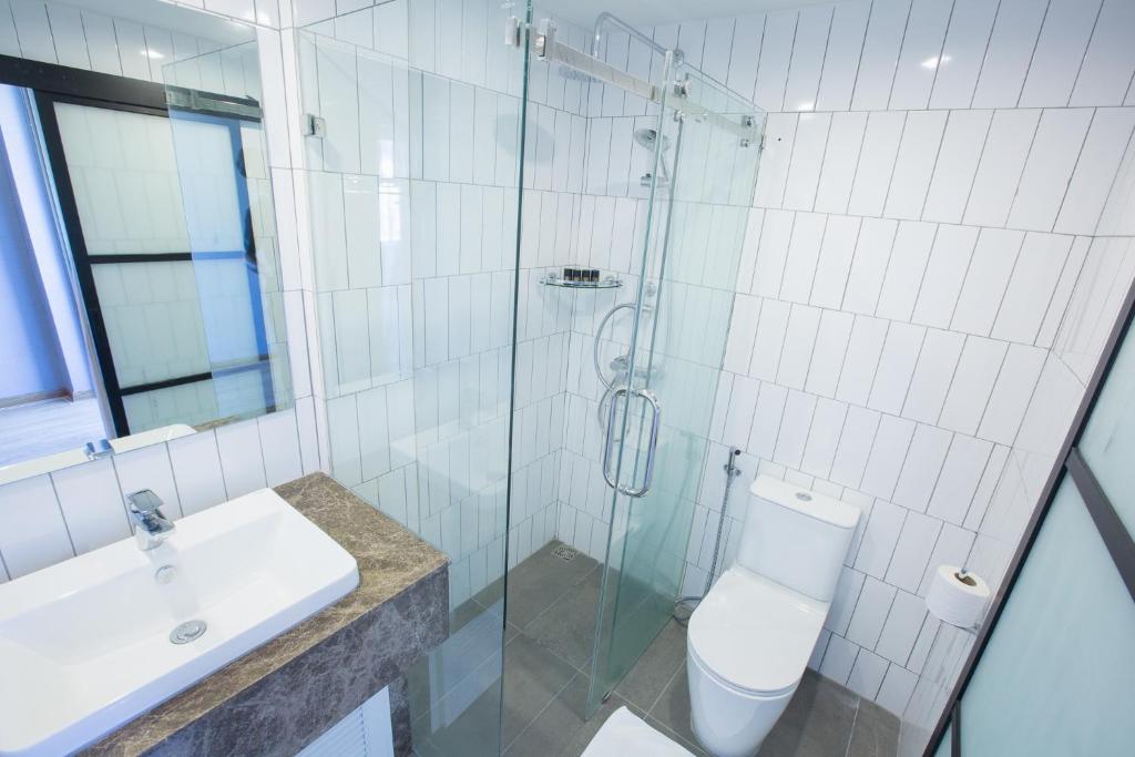 A bright tiled bathroom with a glass-enclosed shower, toilet and countertop sink.