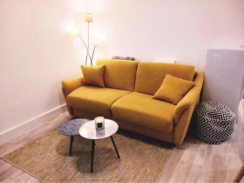- un canapé jaune dans le salon avec une table dans l'établissement Maisonette Cap d 'Agde, au Cap d'Agde