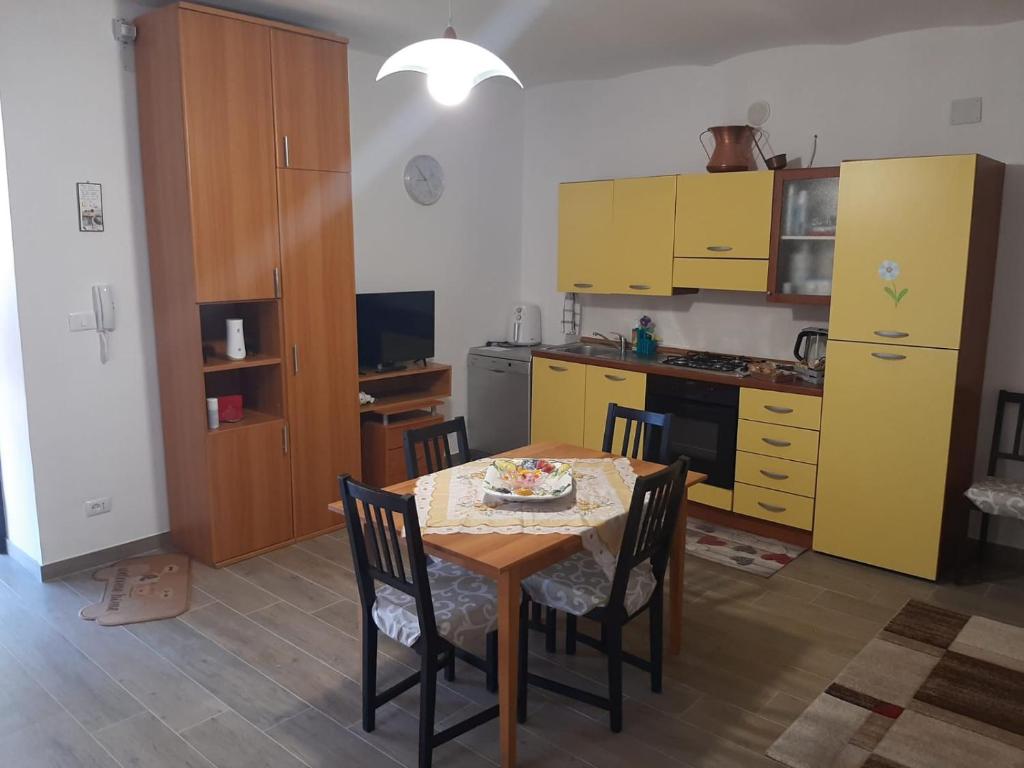 a kitchen with a table and chairs and yellow cabinets at La Casetta dei Sogni in Casalanguida