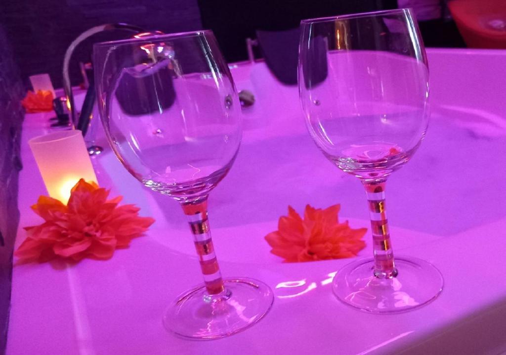 deux verres à vin assis sur une table avec une lumière violette dans l'établissement Heaven Loft, à Yvetot