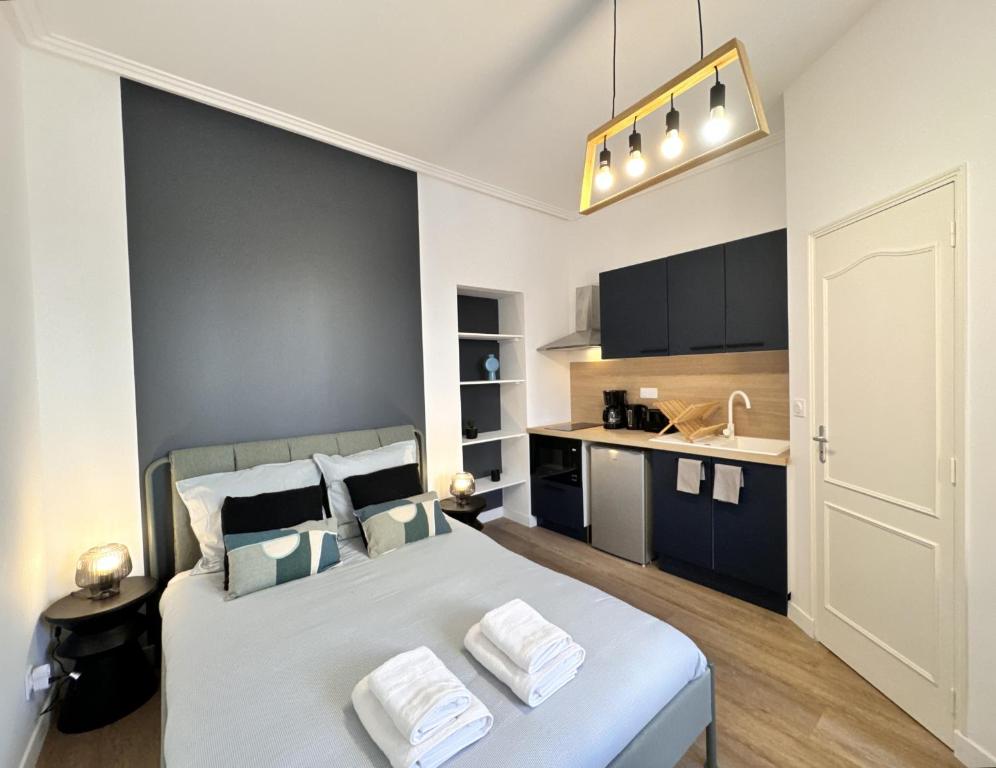 une chambre avec un grand lit blanc et une cuisine dans l'établissement Les studios de la gare - Centre Le Mans - Calme, au Mans