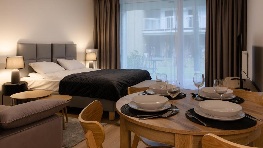 ウェバにあるNadmorska Florina, Sun & Snowのベッドとワイングラスが置かれたテーブルがあるホテルの部屋
