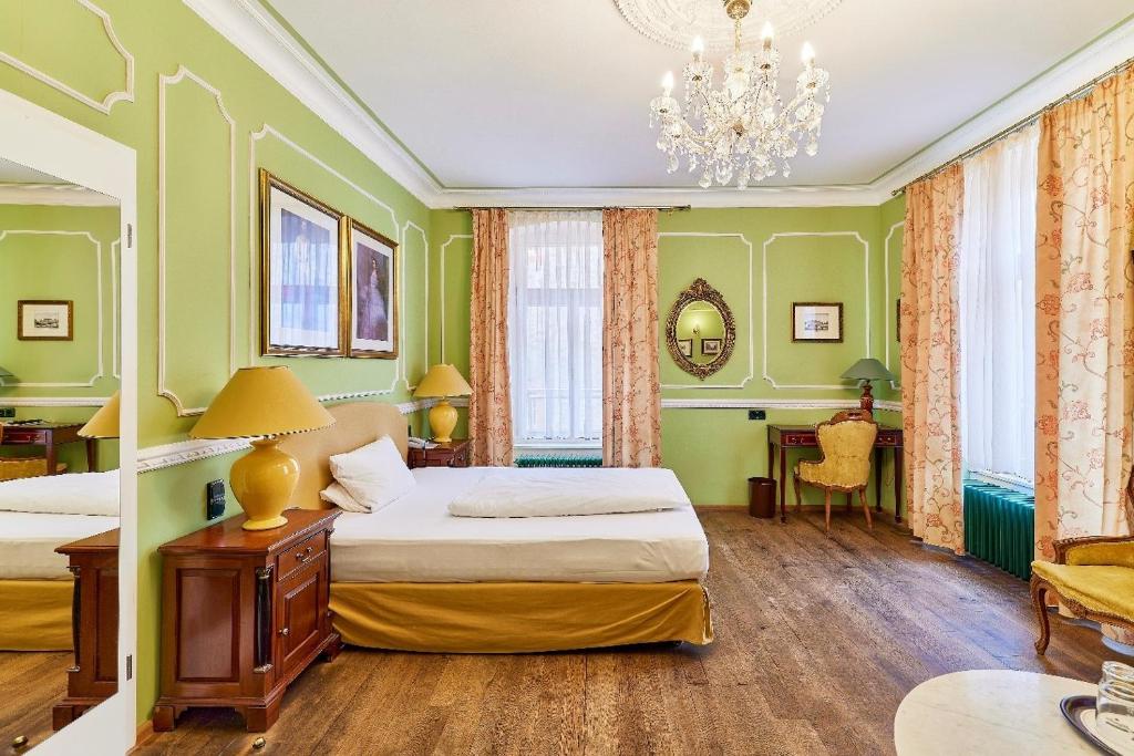 a green bedroom with two beds and a chandelier at HIP Hotel in Heidelberg