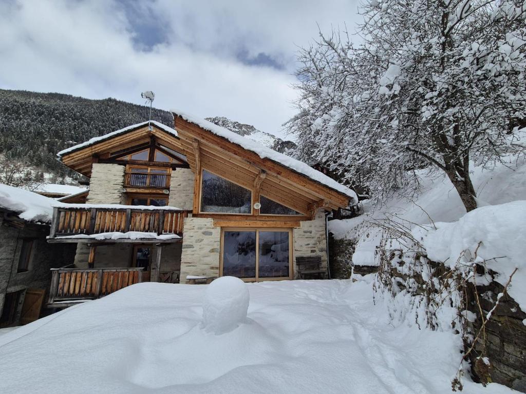 a log cabin with a pile of snow in front of it at La Masure Magnifique chalet - proche domaine St Foy in Sainte-Foy-Tarentaise