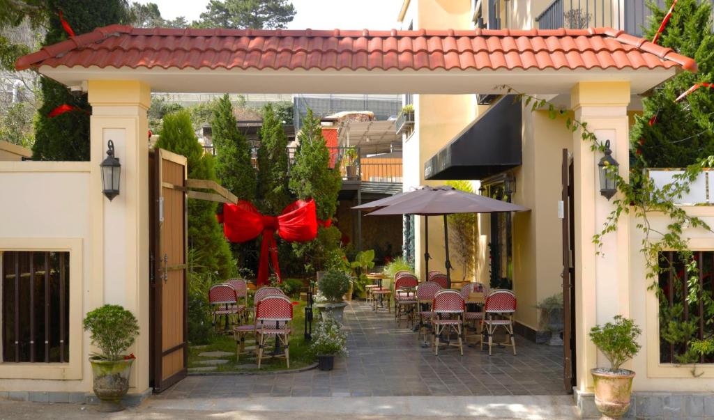een patio met stoelen en tafels met rode bogen bij Hôtel De Da Phu in Da Lat