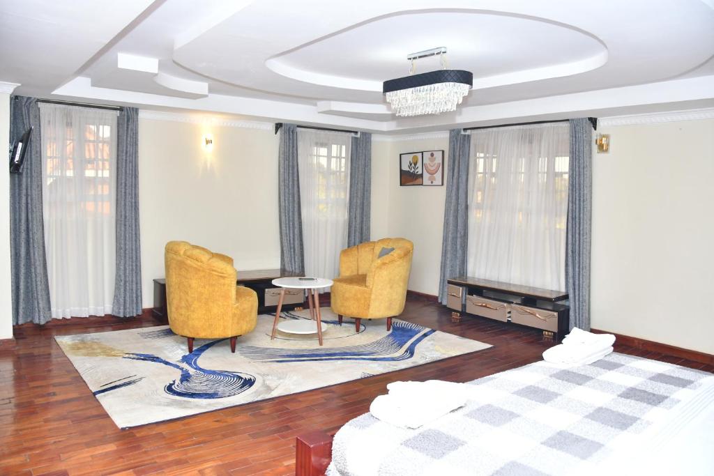 1 dormitorio con 2 sillas, 1 cama y 1 mesa en Melrose Homestay & Garden, en Nairobi